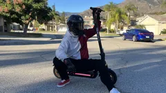 Person in helmet crouching on electric scooter on suburban street