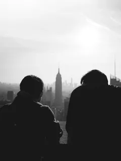 Silhouette of two people near a high-rise building in daylight