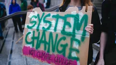 Woman holding 'System Change Not Climate Change' sign at Extinction Rebellion, Trafalgar Square