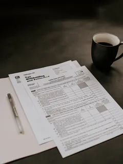 Black ceramic mug next to white printer paper on desk