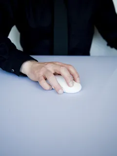 Person holding a white cordless computer mouse in hand