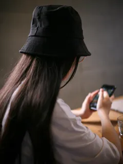 Woman in white shirt holding black smartphone, close-up