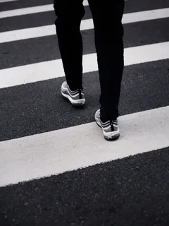 Person wearing black pants and black-white Nike sneakers standing