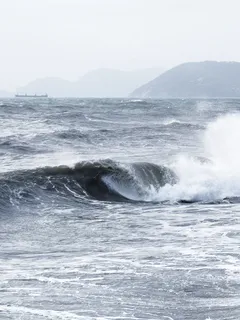 Powerful sea waves crashing on shore under clear sky