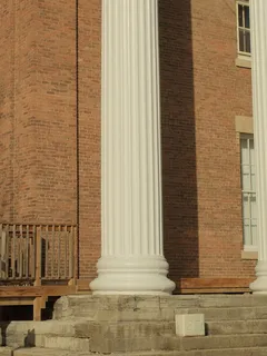 Person sitting on bench outside building under blue sky