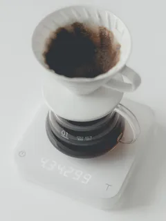 White ceramic mug next to a clear glass container on white background