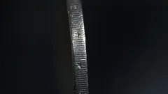 Close-up of a coin's edge with detailed ridges against a dark background