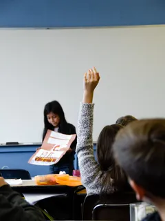Girl raising hand in classroom during lesson